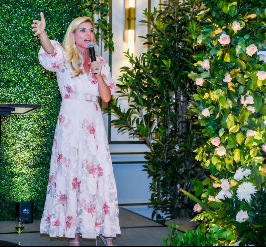 Molly Grantham speaking to a gala crowd in a floral dress