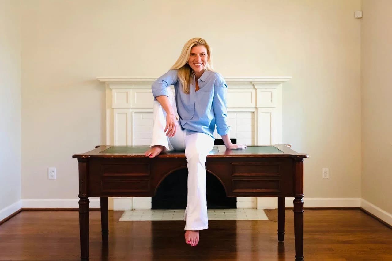 Molly Grantham seated on a desk in front of a fireplace